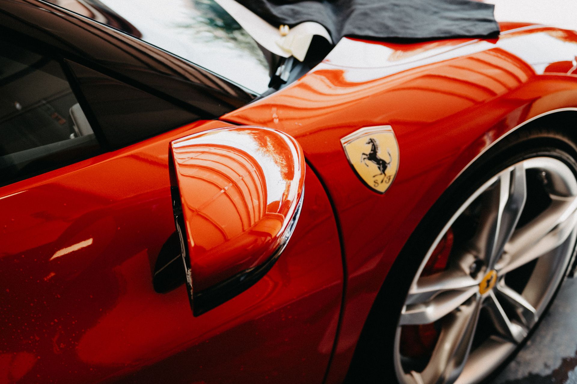 Detailed view of a red sports car featuring a polished exterior and emblem.